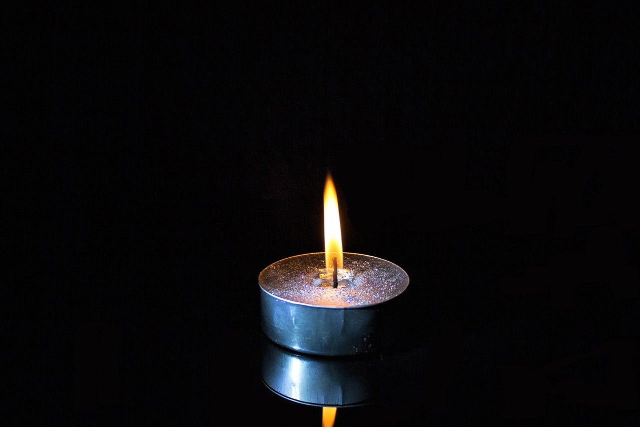 a black background with a single votive candle that is lit