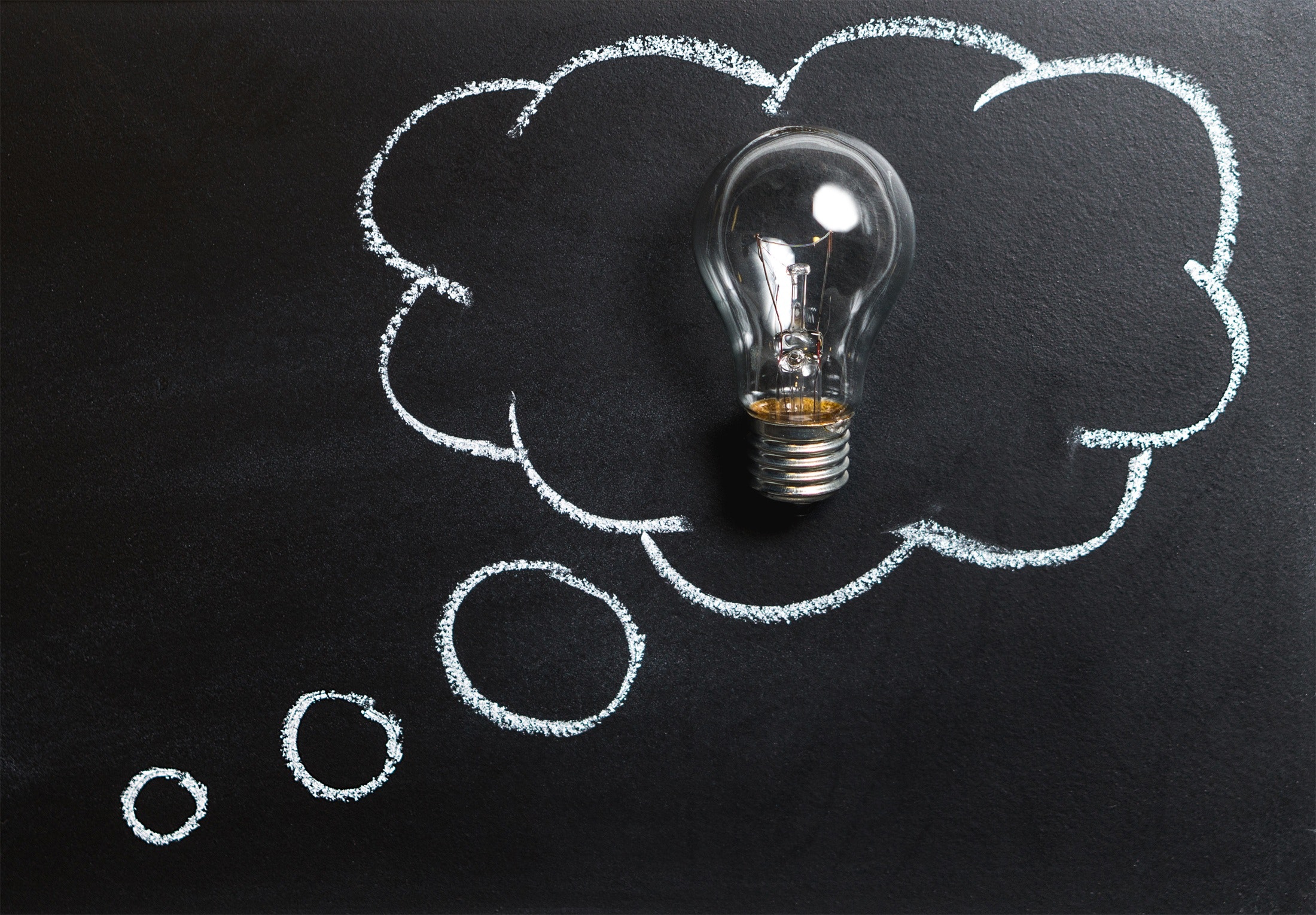 drawing of a thought bubble on a blackboard with a lightbulb in the middle of it