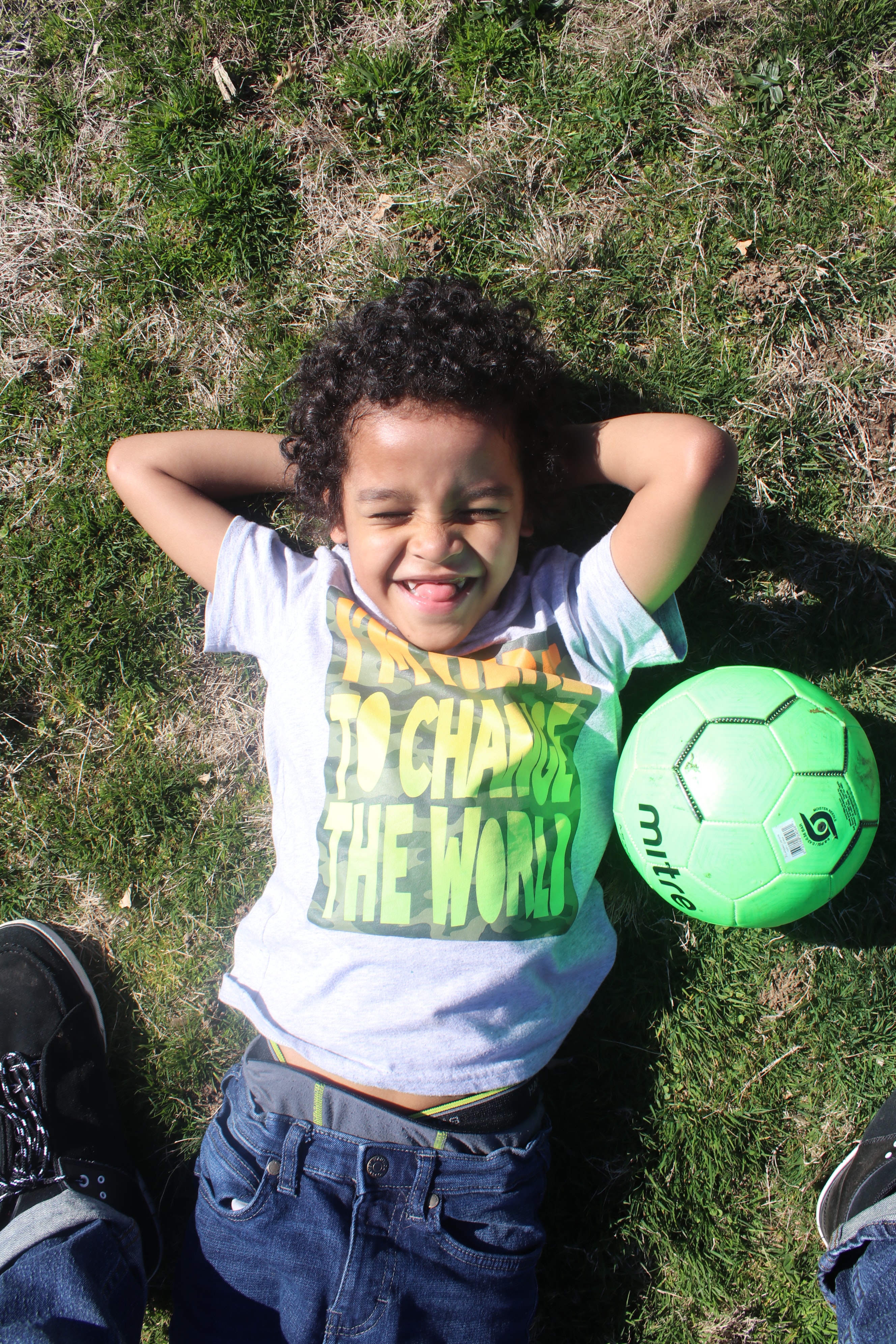 Photo of young child lying on the ground with a soccer ball