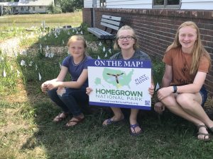 Three girls holding a “Homgrown National Park” sign