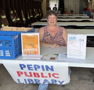 Pepin Public Library information table at the fire station, with Christy smiling