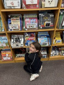 girl smiling in front of a shelf full of books