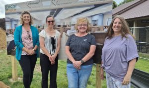 Library director and board in front of building project sign