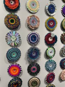 Close view of CD weaving wall hanging showing details of several styles and colors of weaving