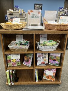 Plum City’s seeds displayed in baskets in a bookcase with gardening books